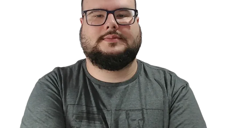 Homem de óculos e camiseta cinza com barba e expressão neutra